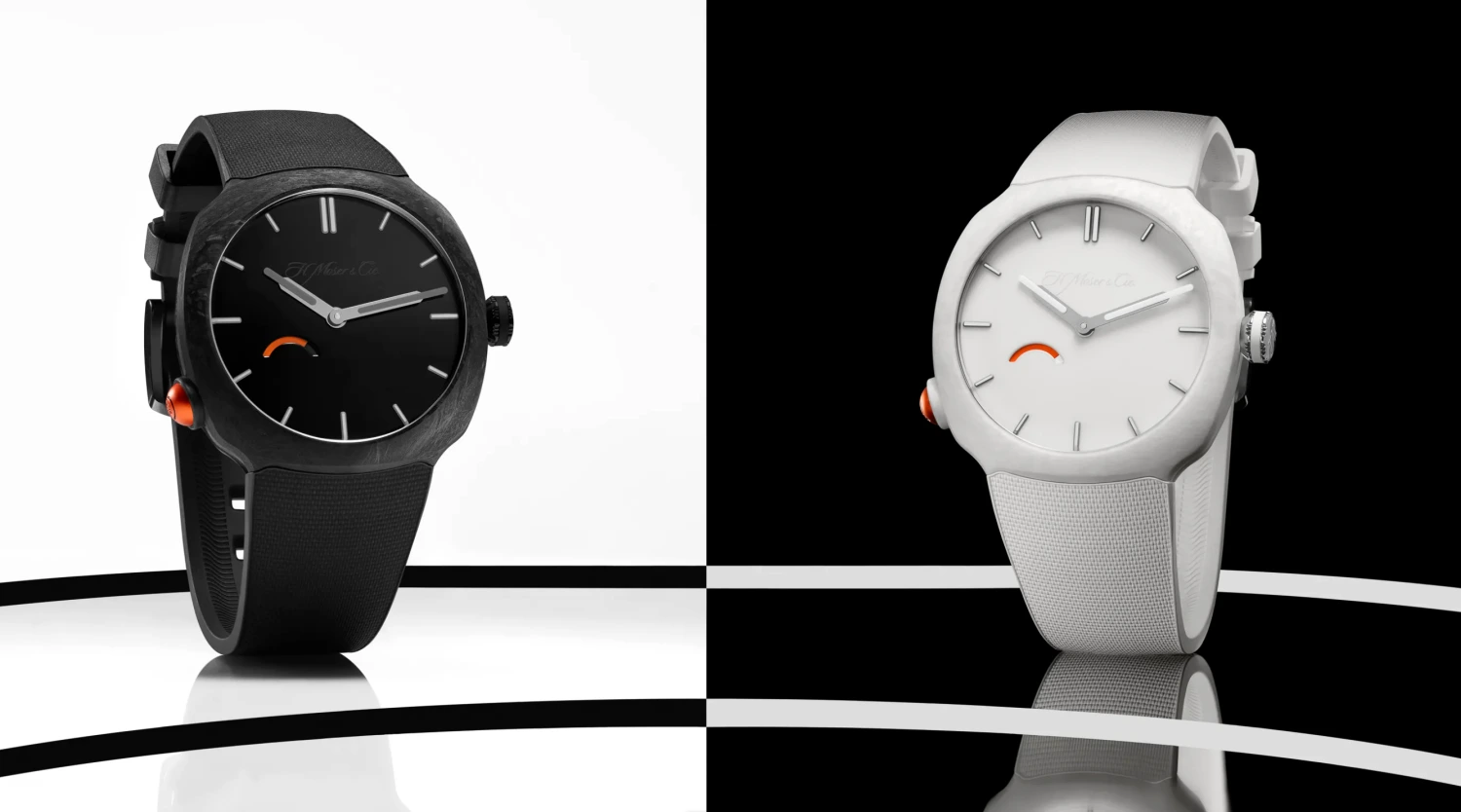 H. Moser & Cie. markasına ait, Streamliner koleksiyonundan biri siyah biri beyaz renkte, kadranında ve yan tarafında dikkat çekici turuncu vurgular bulunan iki modern saat, siyah beyaz zemin üzerinde yansımalarıyla beraber etkileyici bir şekilde sergileniyor.