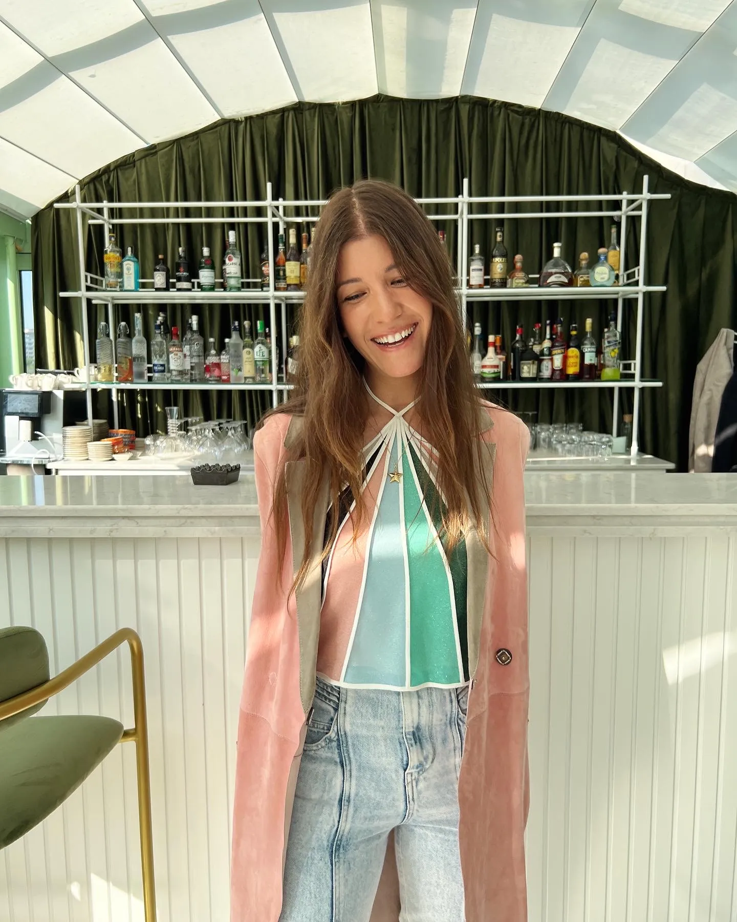 Global moda sahnesinde önemli bir isim olan stylist İpek Ersoy Gelgin, Los Angeles'ta bir barda renkli halter yaka üstü ve pembe ceketiyle neşeli bir ifadeyle poz vererek, ünlü isimlerin stil yolculuklarına eşlik ettiği ve Oscar gecesi perde arkasını anlattığı röportajına eşlik ediyor.