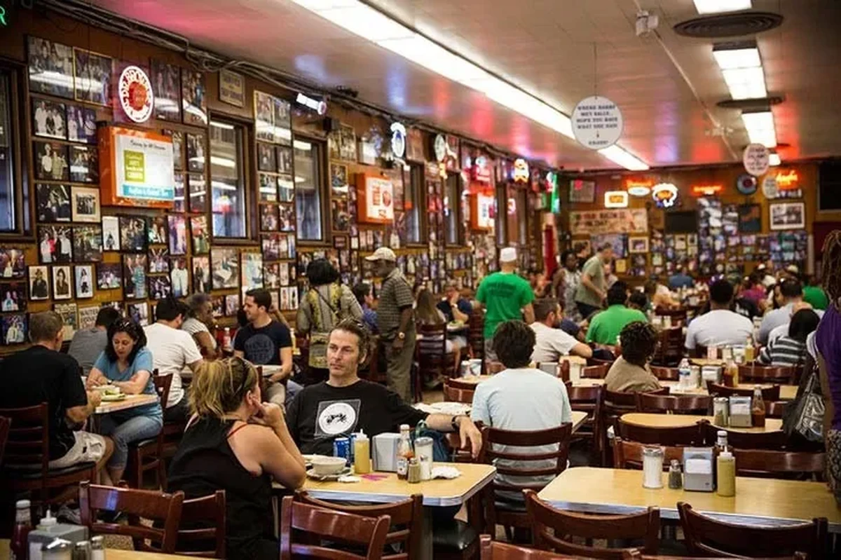 Kalabalık Katz’s Delicatessen’ın içi, duvarlarını süsleyen sayısız fotoğraf ve renkli neon tabelalarla dolu tarihi bir atmosfer sunarken, filmlerde geçen ünlü bu restoranda misafirler When Harry Met Sally sahnesini anımsatan masalarda keyifle yemek yiyor.