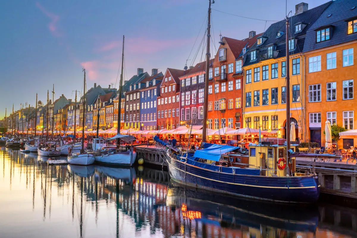 Kopenhag'ın ikonik Nyhavn kanalında, gün batımının yumuşak renkleri altında sıralanmış rengarenk tarihi binalar ve demirli tekneler parıldarken, şehrin bu canlı ve davetkar köşesi en iyi bakery'lerde lezzetli bir mola vermek için mükemmel bir atmosfer sunuyor.