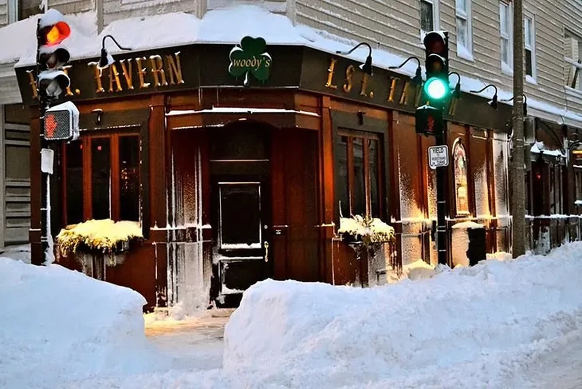 Good Will Hunting filminin çekildiği, dış cephesi koyu renkli ahşapla kaplı L Street Tavern’in kış manzarasını gösteren bu fotoğrafta, binanın tabelası ve Woody’s yonca logosu karla kaplı çatının altında belirginleşirken, kaldırımda biriken kar yığınları ve biri kırmızı, diğeri yeşil yanan trafik lambaları filmlerde geçen bu ikonik mekanın soğuk ama davetkar atmosferini yansıtıyor.