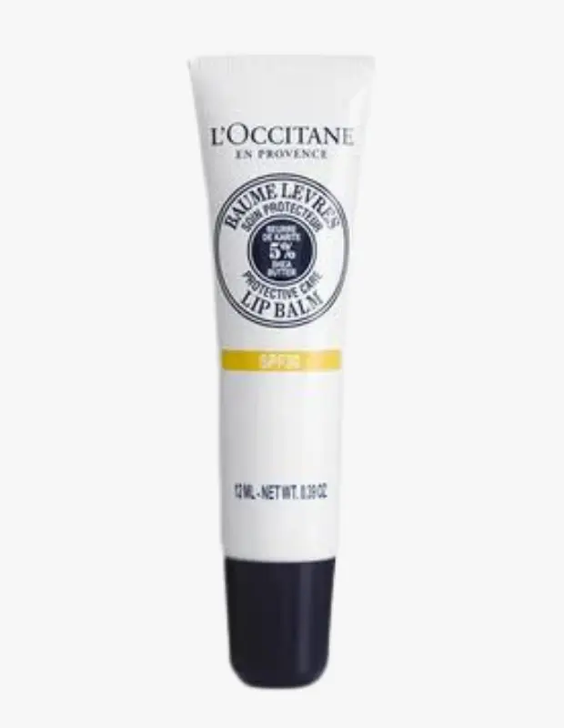 Beyaz bir arka plan üzerinde dikey konumlanmış, üst kısmında L'OCCITANE EN PROVENCE logosu bulunan, ortasında yüzde 5 shea yağı içeren koruyucu dudak balmi yazısı ve altında SPF30 ibaresi yer alan beyaz ve koyu mavi renkli 12 ml'lik bir L'OCCITANE spfli dudak balmi tüpü.