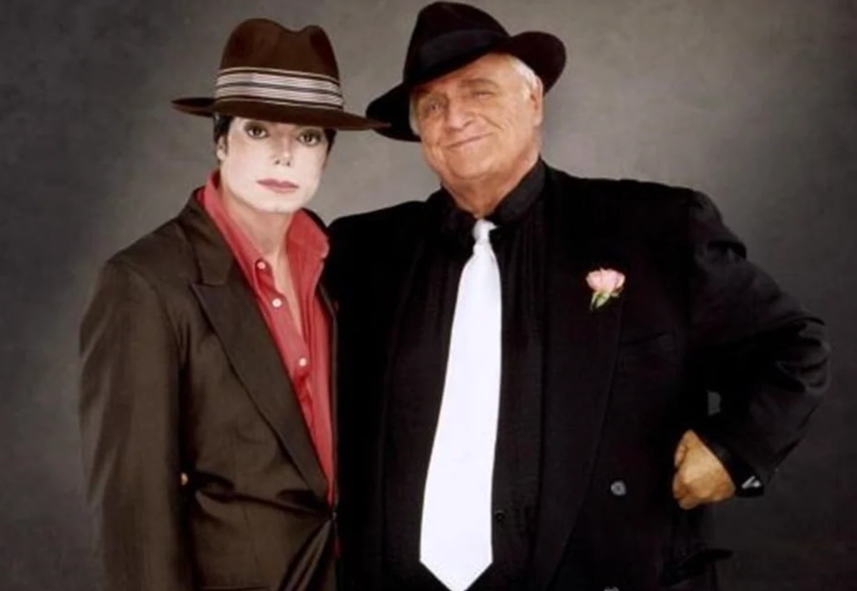 Marlon Brando ile ikonik You Rock My World işbirliklerini akla getiren resmi bir fotoğraf çekiminde, şık fötr şapkalar ve takım elbiseler içinde yan yana poz veriyorlar; Jackson kahverengi şapkası ve kırmızı gömleğiyle ciddi bir ifade sergilerken, Brando siyah şapkası, beyaz kravatı ve yakasındaki pembe gülle memnuniyetle gülümsüyor.