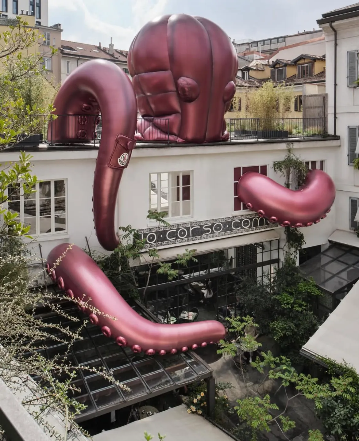 Milano'da 10 Corso Como binasının çatısından ve cephesinden sarkan, Moncler logosu taşıyan pembe şişme ahtapotun eğlenceli ve dikkat çekici enstalasyonu, Milano Design Week 2026'nın yaratıcı atmosferini yansıtıyor.