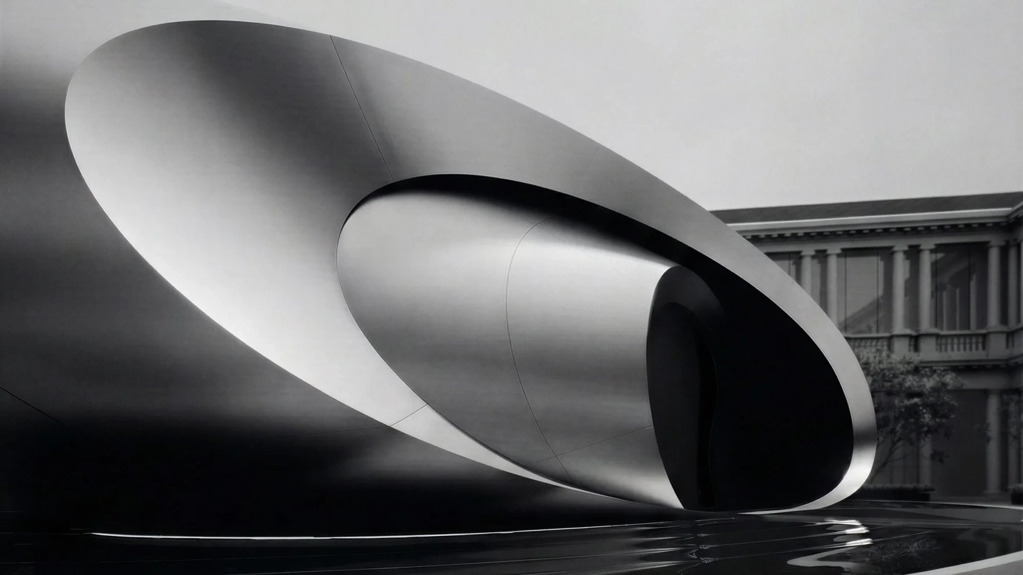 Milano Design Week 2026 kapsamında, Audi ve Zaha Hadid Architects iş birliğiyle oluşturulan The Origin enstalasyonu, titanyum renkli akışkan hatlara sahip fütüristik bir portalı yansıma havuzu üzerinde, klasik mimariye sahip bir yapının önünde sergileyerek geçmişle geleceği meditatif bir diyalogla birleştiriyor.