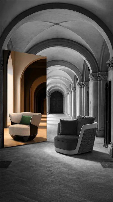 Milano Design Week 2026'nın ruhunu yansıtan bir enstalasyonda, tarihi kemerli bir saray koridorunun gri tonlarındaki görkemi, modern yaşam formlarını temsil eden renkli bir aynadan yansıyan bej ve yeşil detaylı modern koltuk ile sağda duran gri bir koltukla büyüleyici bir tezat oluşturarak geçmişle geleceğin tasarım diyalogunu vurguluyor.