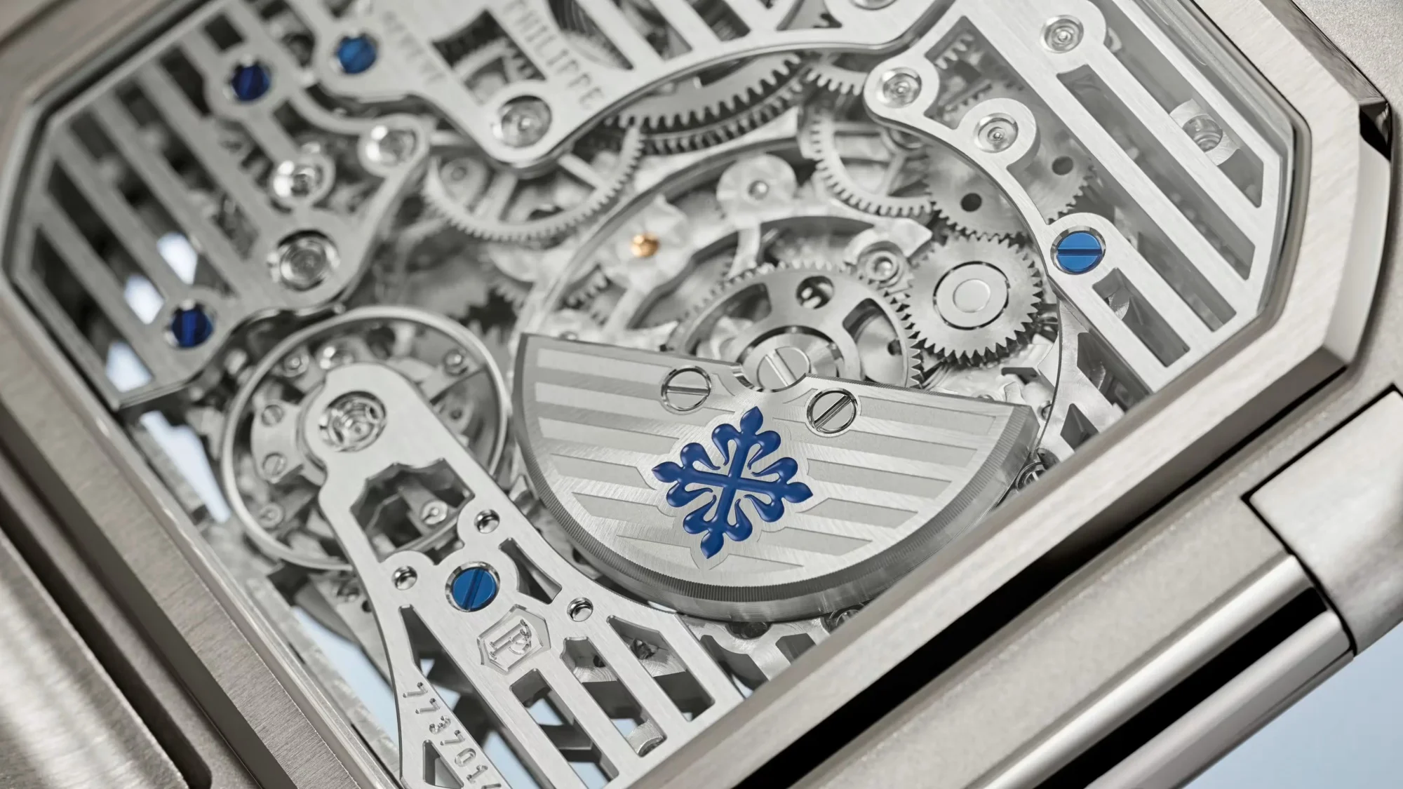 Patek Philippe Cubitus Perpetual Calendar 5840P platin bir saatin arka kapağından görünen karmaşık iç mekanizması, birbirine kenetlenmiş hassas dişlileri, zarif köprüleri, dikkat çekici mavi vidaları ve markanın ikonik Calatrava çapraz logosunu taşıyan oyulmuş rotoru gözler önüne seriyor.
