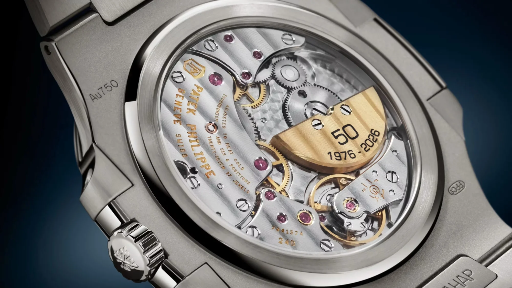 Çelik Patek Philippe Nautilus 50. yıl özel saatinin şeffaf arka kapağından görünen, 50 1976-2026 yazılı altın rotoru, karmaşık dişlileri ve yakut yataklarıyla zarif işlenmiş mekanizması.