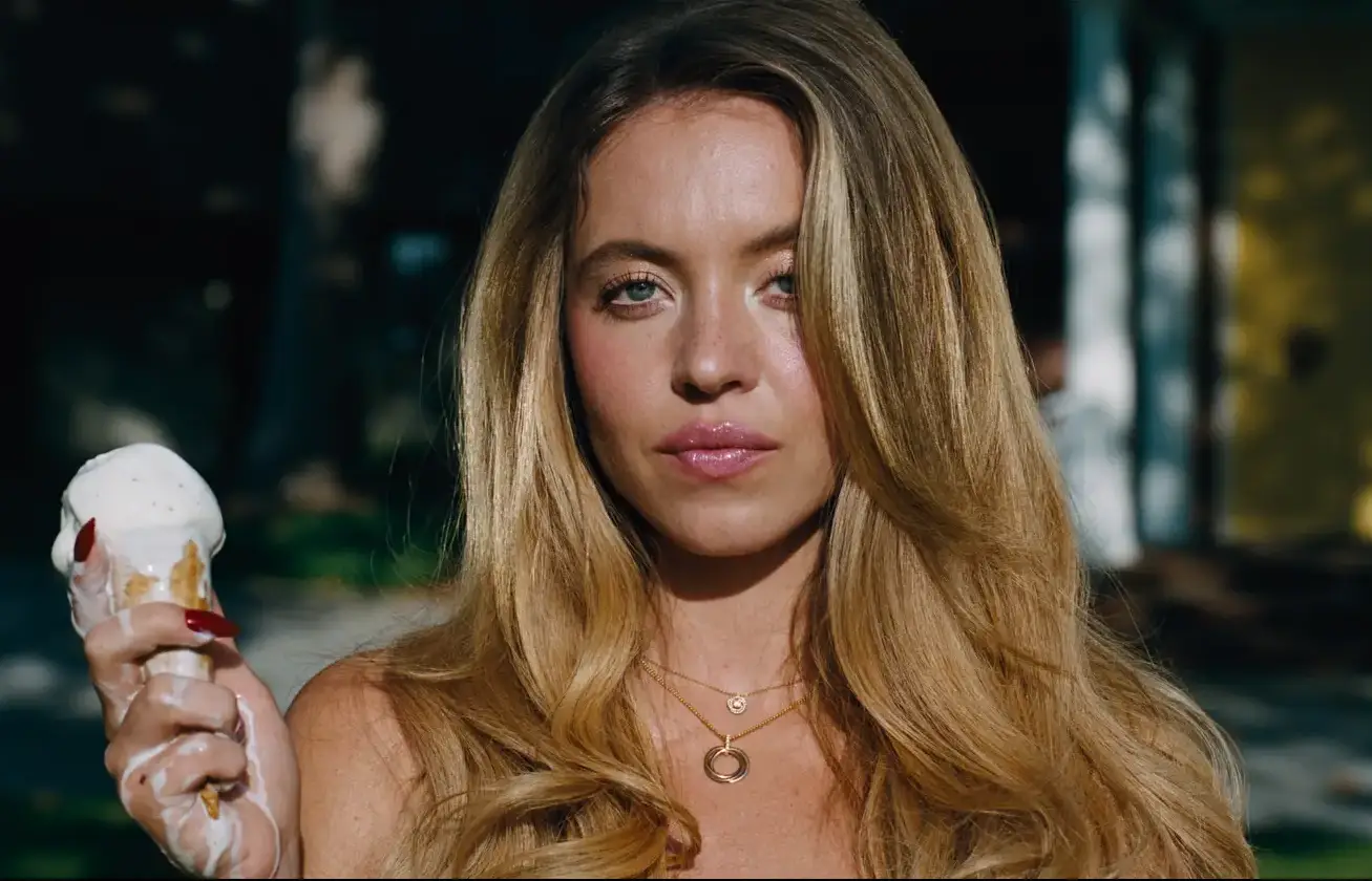 Uzun dalgalı sarı saçları, parlak mavi gözleri ve pembe dudaklarıyla doğrudan kameraya bakan Sydney Sweeney, erimiş vanilyalı dondurma bulaşmış elinde bir külah tutarken, Euphoria Sezon 3'ten hatırlatıcı bir sahneyi anımsatıyor.