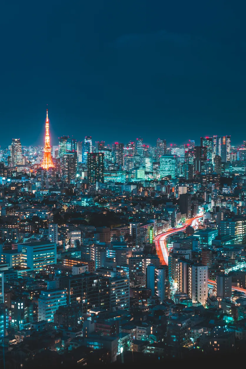 Tokyo şehrinin gece manzarası, ışıl ışıl binaları, ikonik Tokyo Kulesi ve uzun pozlama efektiyle belirginleşen hareketli yollarıyla, bu büyük şehri nasıl gezilir sorusuna canlı bir arka plan sunuyor.