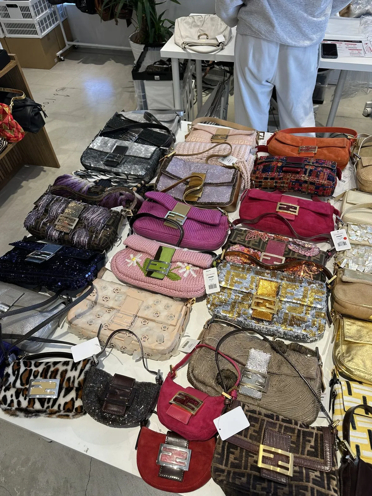 Tokyo'daki bir vintage mağazasında, her biri farklı renk, doku ve desene sahip, pullu, örgülü, kürklü ve süet gibi çeşitli malzemelerden yapılmış onlarca ikonik Fendi Baguette çanta bir masanın üzerinde özenle sergileniyor.