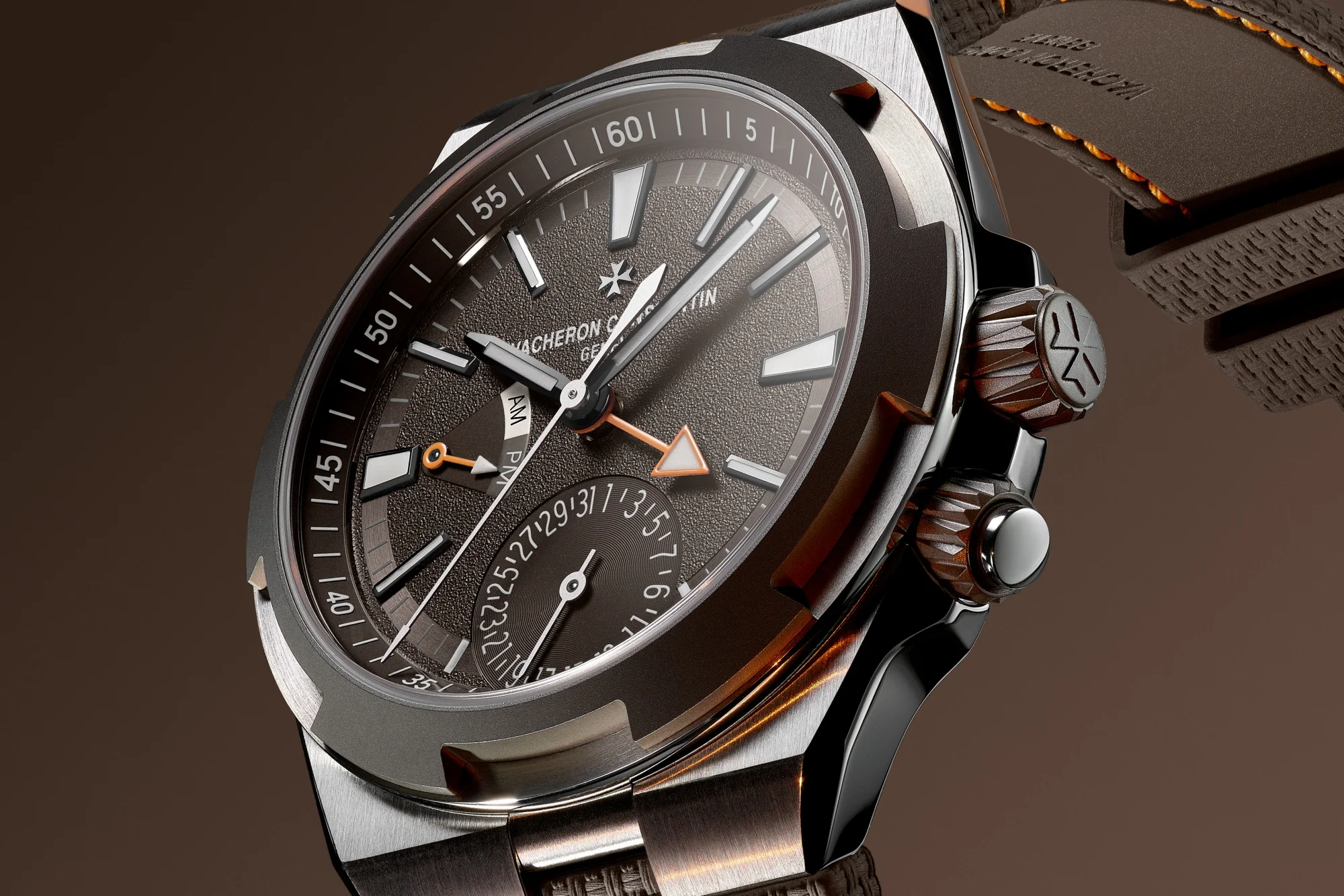 Koyu renkli, dokulu kadrana sahip, parlak ibreleri, Vacheron Constantin Maltese Haçı logosu, tarih alt kadranı ve turuncu okla belirginleştirilmiş Dual Time göstergesiyle Vacheron Constantin Overseas Dual Time saati, global zaman takibini ve yön noktalarını çağrıştıran fırçalanmış metal kasası ve sağdaki kurma koluyla öne çıkıyor.