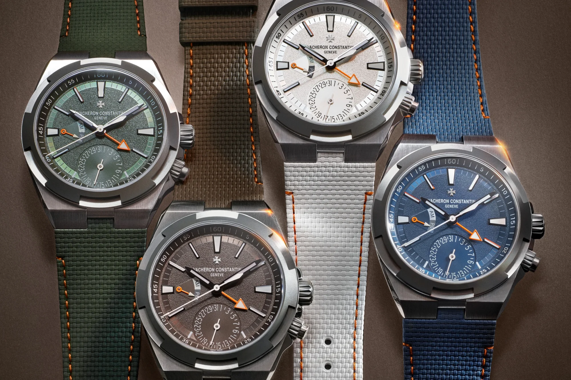 Dört adet Vacheron Constantin Overseas Dual Time saati, yeşil, gümüş, gri ve mavi kadranları ile uyumlu kumaş kayışları, paslanmaz çelik kasaları ve çift zamanlı, tarih gösterme özellikleriyle dikkat çekerek farklı yönlere işaret eden tasarımlarını sergiliyor.