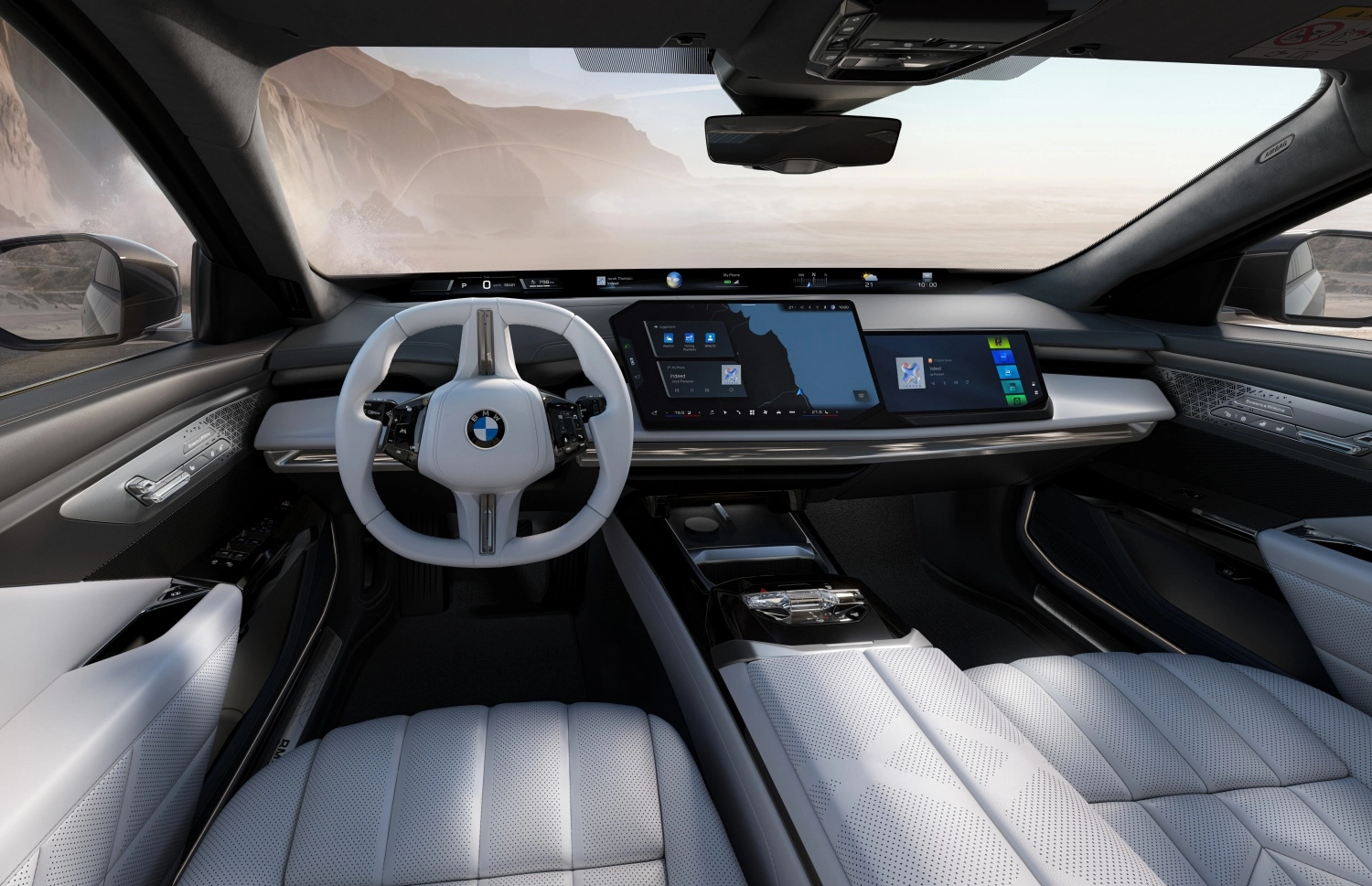 Yeni BMW i7'nin fütüristik iç mekanı, beyaz direksiyon simidi, kavisli geniş dijital ekranı ve delikli açık renkli deri koltuklarıyla Neue Klasse tasarım dilini yansıtan, dışarıda görünen çöl manzarasıyla kontrast oluşturan modern ve ferah bir görünüm sunuyor.