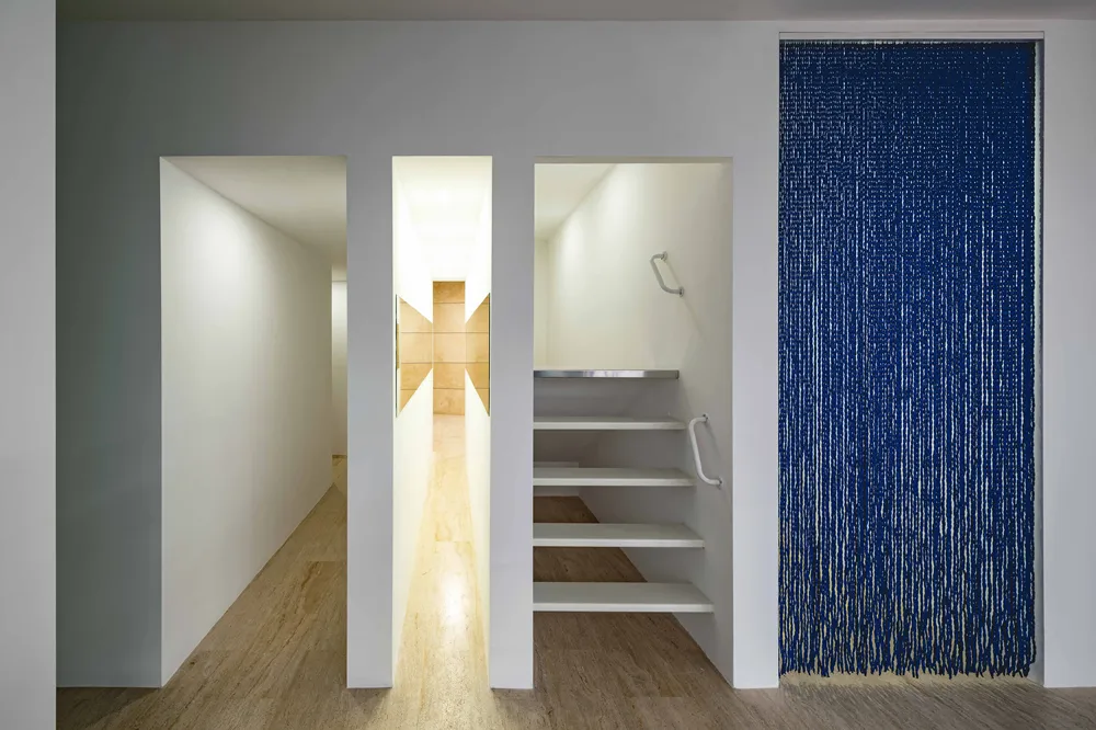 Beyaz duvarların ve açık renk yer karolarının hakim olduğu minimalist bir sergi alanında, sağda yoğun mavi ipliklerle oluşturulmuş, dokulu ve dinamik bir sanat perdesi, ortada sonunda geometrik bir desene ulaşan ışıklı dar bir geçit ve solda basamaklı bir yapı içeren düzenleme, Yoko Ono'nun İstanbul sergisinden çağdaş bir enstalasyon sunuyor.
