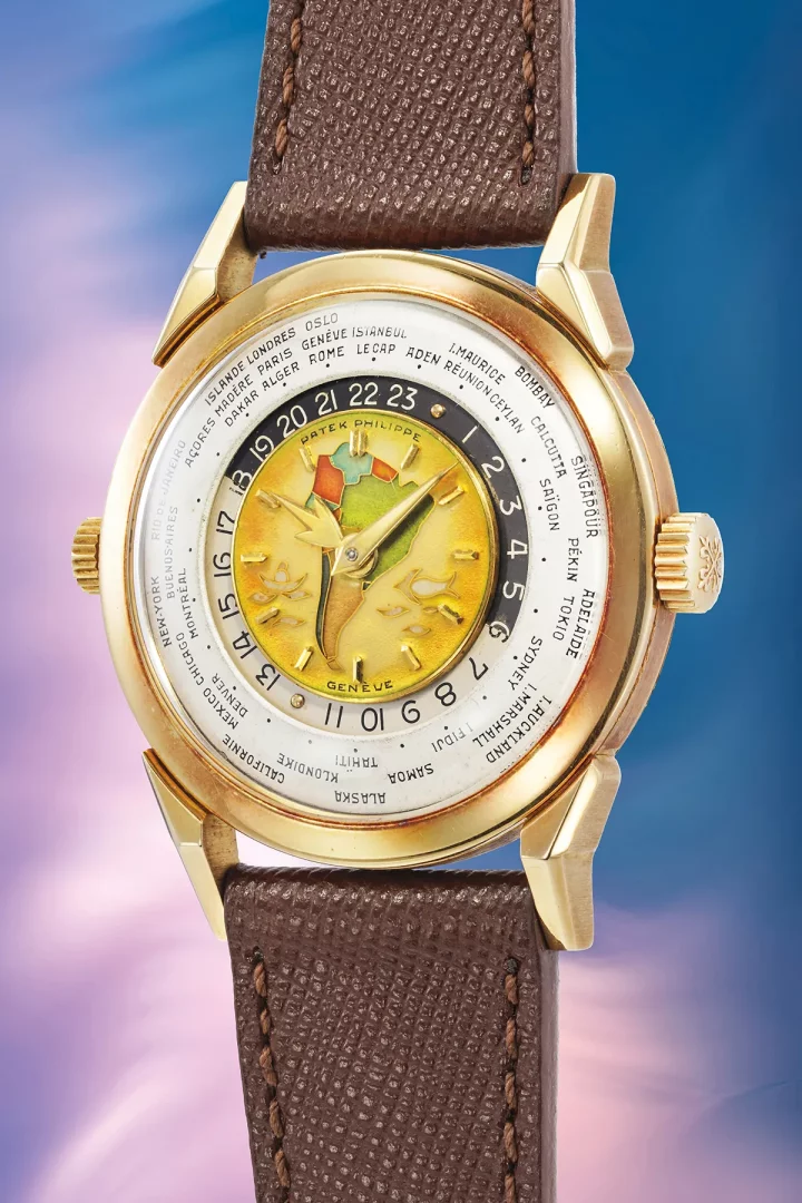 Kahverengi deri kayışlı, ortasında Avrupa ve Afrika haritasının emaye işleme ile betimlendiği, Patek Philippe Genève yazılı, Ref. 2523 model altın World Time kol saatinin kadranında 24 saatlik zaman dilimlerini ve farklı dünya şehirlerinin isimlerini gösteren halkalar belirgin şekilde görülüyor.