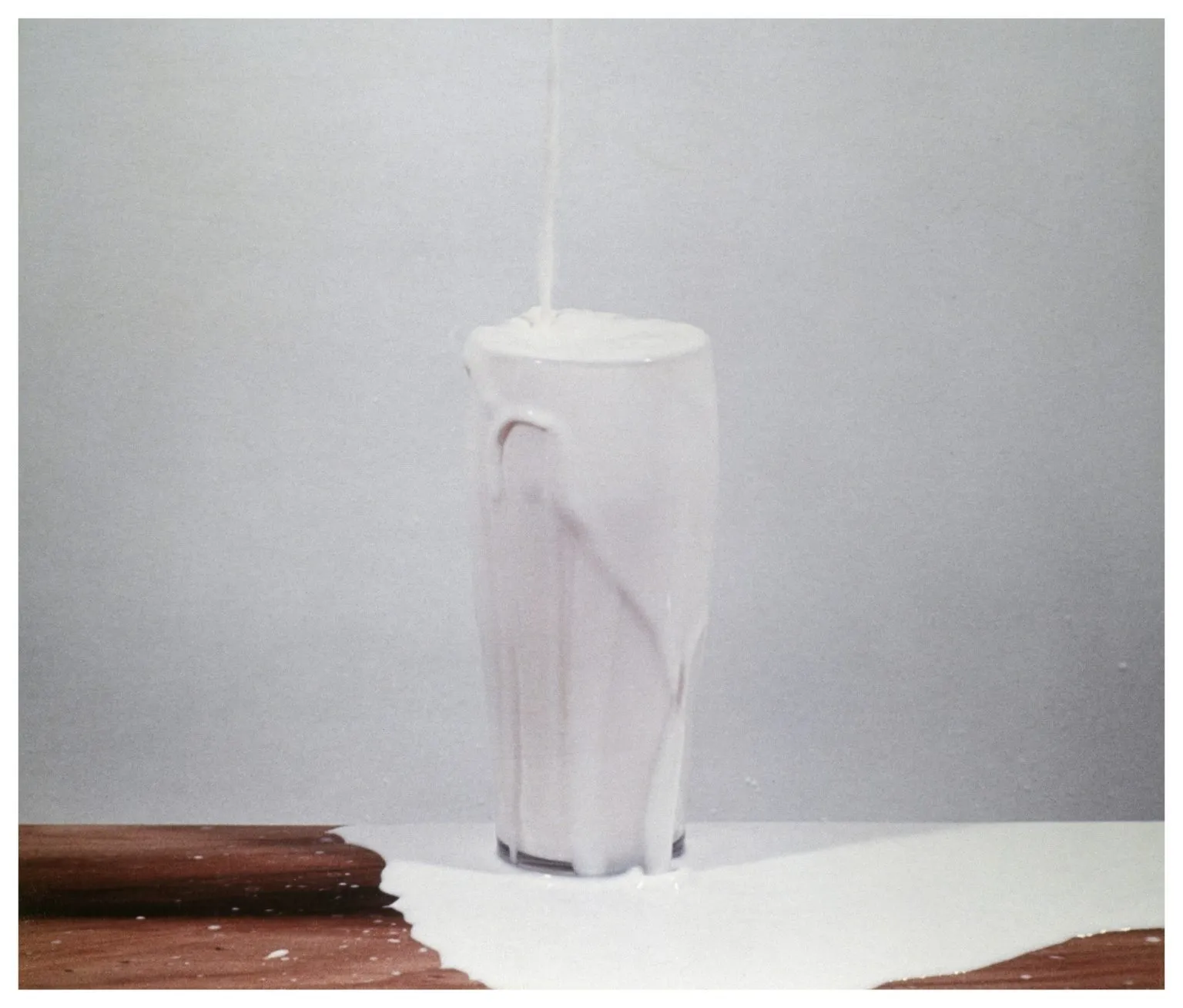 David Lamelas'ın Dia Art Foundation için yarattığı bu sanat eserinde, gri bir arka plan ve beyaz bir masa üzerinde, içine yukarıdan dökülen süt ile taşan ve etrafa yayılan, uzun, şeffaf bir bardak görülüyor.