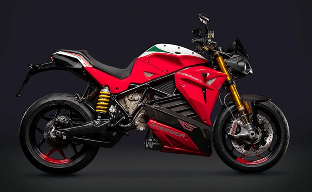 Koyu arka planda yandan çekilmiş bu Energica Eva Ribelle RS-1 elektrikli naked motosiklet, kırmızı renk ağırlıklı gövdesi, beyaz ve yeşil şerit detayları, altın rengi ön süspansiyonları ve jantlarındaki kırmızı vurgularıyla dikkat çekici bir tasarıma sahip.