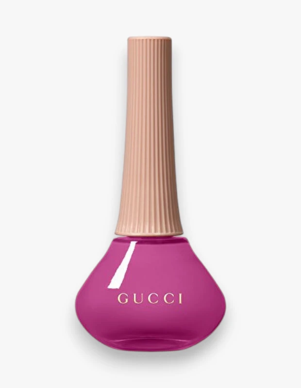 Ortasında altın rengi GUCCI yazısı bulunan, gözyaşı damlası şeklinde parlak fuşya renkli bir oje şişesi ve şişenin üst kısmında dikey çizgili, ten rengi silindirik bir kapak yer alıyor, bu özel Vernis à Ongles (oje) tasarımı dikkat çekiyor.