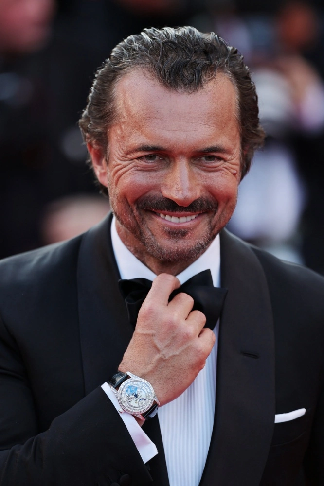 William Abadie, Cannes kırmızı halısında, siyah smokini ve beyaz gömleğiyle gülümseyerek papyonunu düzeltirken, sol bileğindeki göz alıcı pırlanta bezeli Chopard LUC Tourbillon saat ile tüm dikkatleri üzerine çekiyor.