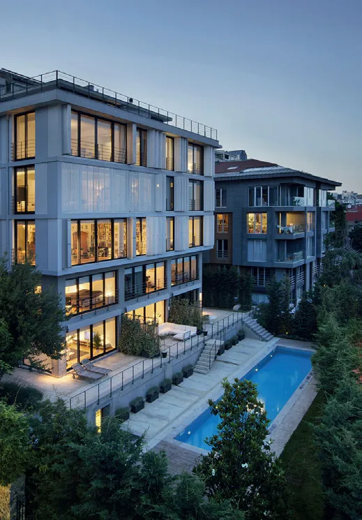 Alacakaranlıkta parlayan ışıklarıyla Ada Residence'ın modern mimarisini sergileyen bu görselde, çok katlı binanın geniş pencereleri, balkonları ve özel yüzme havuzu, Karaören Mimarlık imzası taşıyan estetik ve fonksiyonel tasarımı vurguluyor.