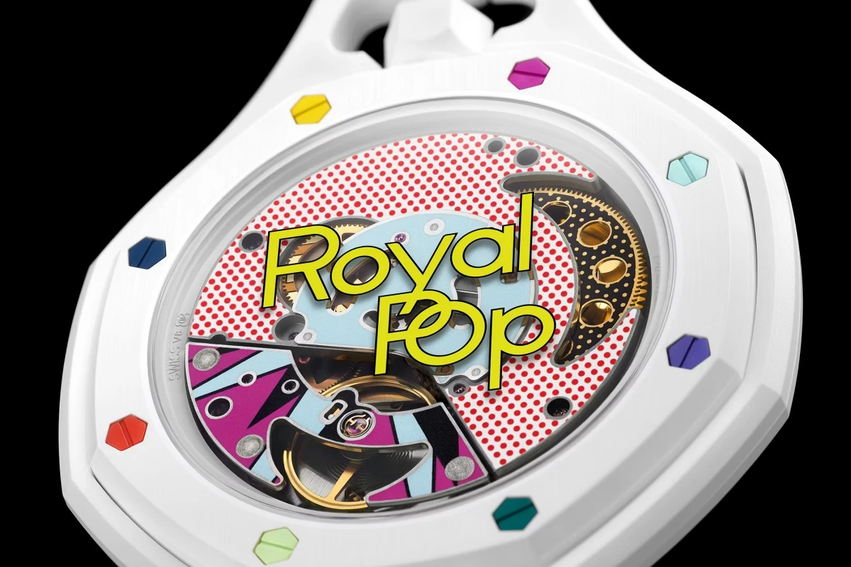 Audemars Piguet Swatch iş birliğiyle üretilen Royal Pop cep saatinin beyaz arka kapağında, pop art tarzı renkli iç mekanizma detayları ve üzerinde belirgin sarı fontla Royal Pop yazısı dikkat çekiyor, kenarındaki parlak altıgen vidalar tasarıma neşe katıyor.