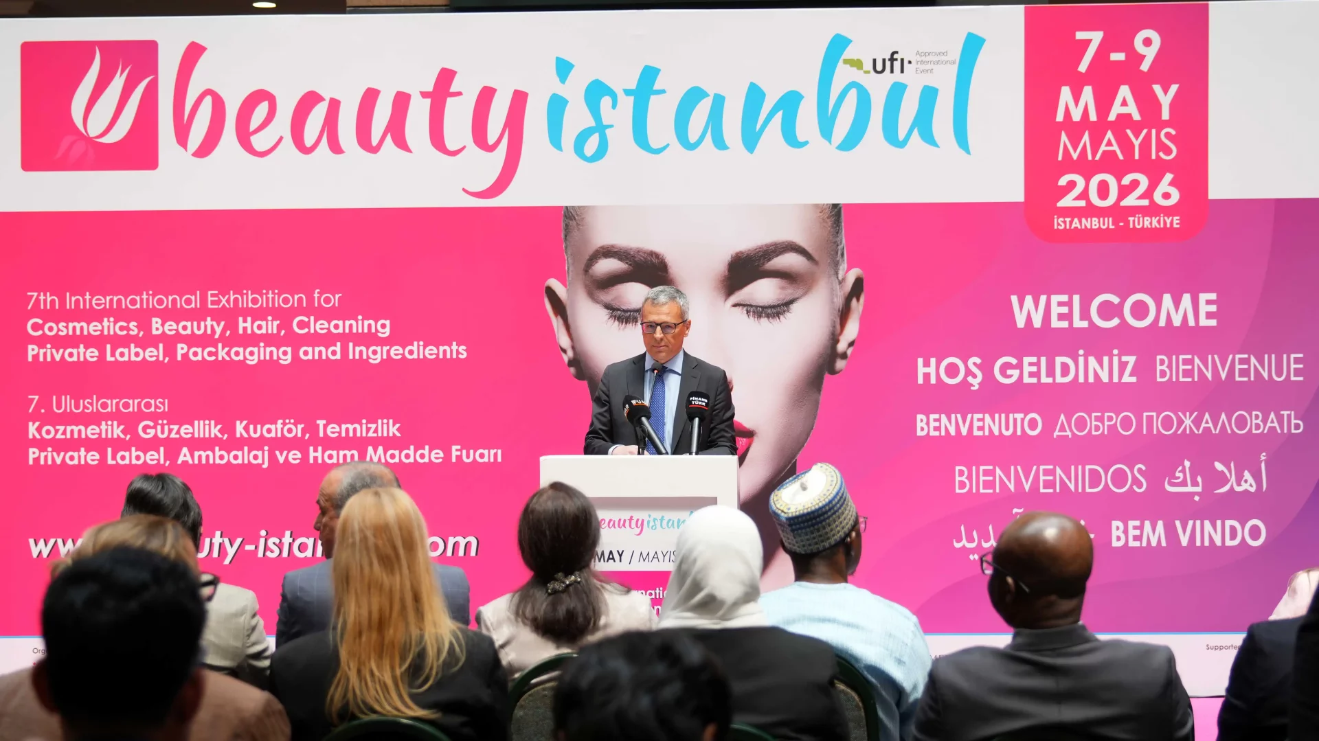 7-9 Mayıs 2026 tarihleri arasında İstanbul'da düzenlenecek olan 7. Uluslararası Kozmetik, Güzellik, Kuaför, Temizlik, Private Label, Ambalaj ve Ham Madde Fuarı Beauty Istanbul'un açılışında, bir konuşmacı dinleyiciler önünde pembe bir pankartın önünde podyumda konuşma yapıyor, markaların bu Mayıs ayındaki yeni gelişmelerini ve iş birliklerini öne çıkarıyor.