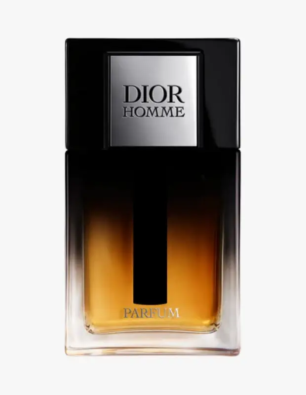 Üzerinde Dior Homme yazan gümüş renkli etiketli siyah kapaklı, içindeki kehribar rengi sıvının şeffaf cam şişeden yansıdığı ve alt kısmında PARFUM kelimesi bulunan bu modern tasarım parfüm şişesi, erkek parfümleri kategorisindeki lüks ve çekici kokuları temsil ediyor.