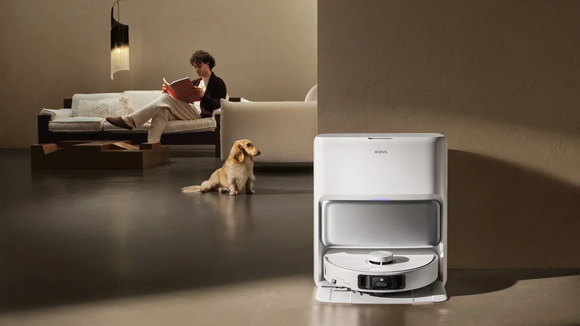 Modern bir oturma odasında, beyaz bir MOVA robot süpürge şarj istasyonuyla birlikte zeminde dururken, hemen yanında oturan tüylü bir köpek ve kanepede kitap okuyan bir kişi evcil hayvanlarla yaşamı kolaylaştıran teknolojik temizlik çözümlerini gösteriyor.