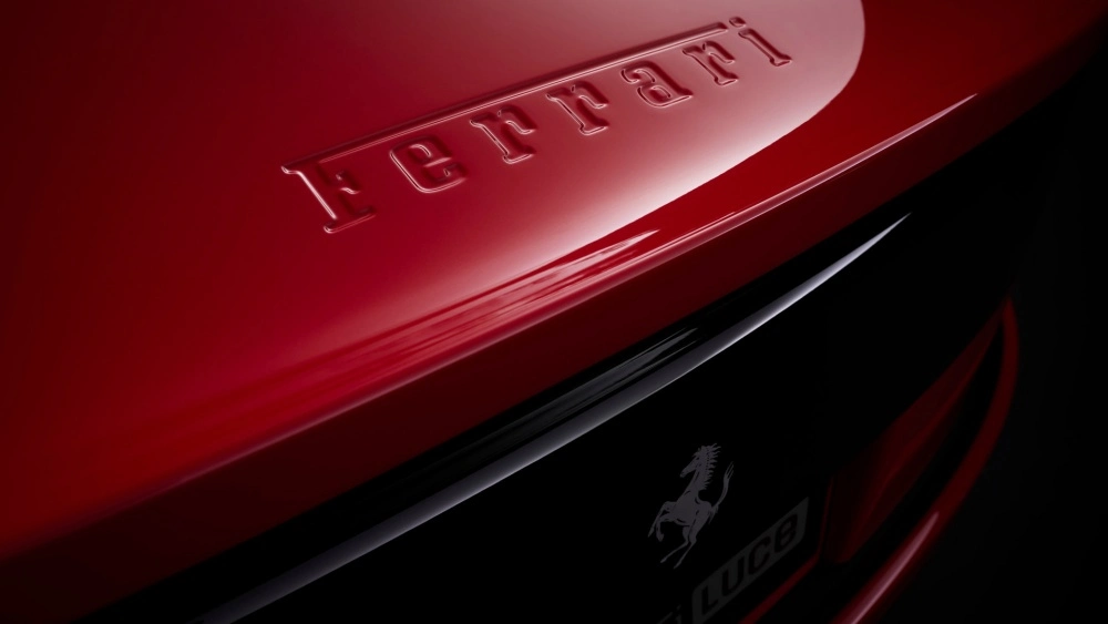 Koyu bir arka plan üzerinde, parlak kırmızı bir yüzeyin üzerine kabartma olarak işlenmiş Ferrari yazısı, aracın elektrikli Ferrari Luce modeline ait olduğunu belirten zarif at logosu ve Luce isminin de göründüğü bir detay.