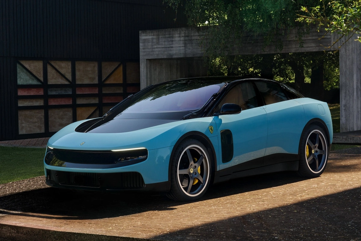 Modern ve şık bir görünüme sahip, siyah tavanı, ince LED farları ve karakteristik sarı fren kaliperleri olan spor jantlarıyla dikkat çeken, bir evin önünde park edilmiş elektrikli Ferrari modelinin, göz alıcı luce mavi dış tasarımını detaylarıyla gösteren bir fotoğraf.