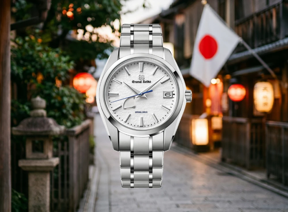 Beyaz kar tanesi desenli kadranı, mavi saniye ibresi ve gümüş renkli kasa ve bileziğiyle öne çıkan şık Grand Seiko Snowflake Spring Drive erkek kol saati, geleneksel Japon sokağı ve dalgalanan bayrak fonunda zarifçe duruyor.