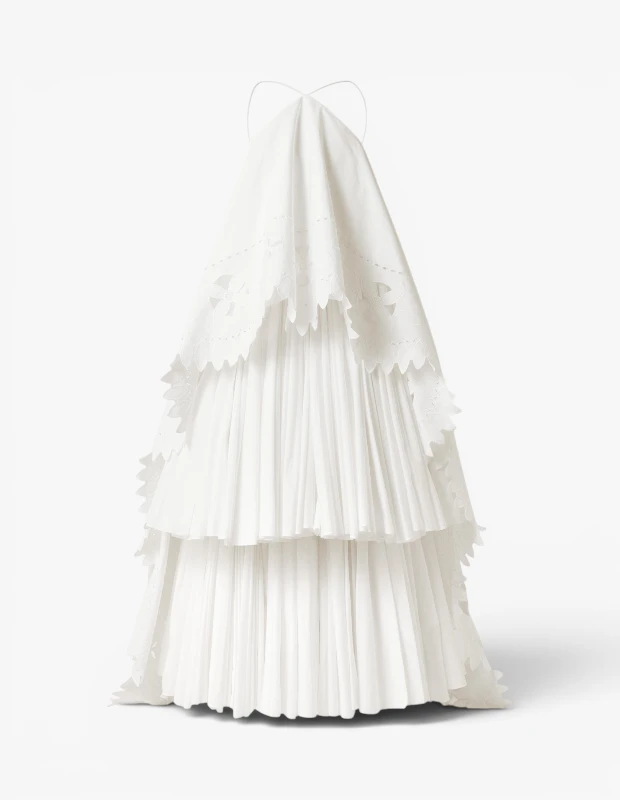 Marka Adı: Jacquemus
Ürün Adı: Jacquemus Kadın Provençale Elbise
Ürün Cinsiyeti: Kadın
Ürün Tipi: Elbise
Ürün Sezonsallığı: İlkbahar/Yaz
Ürün Çeşidi: Abiye Elbise
Ürün Özellikleri: Beyaz renkli, katmanlı ve hacimli bir maksi abiye elbisedir. Üst katmanda çiçek desenli brode ve fisto işlemeler bulunurken, alt katmanlar zarif pilise detaylarıyla hareket kazanmıştır. Fisto kenarlara sahip volanlı katmanlar, elbiseye romantik ve akışkan bir görünüm kazandırır. İnce askılı, zarif halter yaka kesimi ile tamamlanmıştır. Pamuklu veya benzeri tok bir kumaş yapısına sahip olduğu, piliselerini ve volan formunu koruduğu tahmin edilmektedir.
Öne Çıkan Detaylar:
- Çiçek desenli brode ve fisto işlemeli üst katman
- Hacimli, pilise detaylı ve fisto kenarlı katmanlı etek tasarımı
- İnce askılı, zarif halter yaka kesimi
Kimler Kullanıyor?: Zamansız ve sofistike bir stil anlayışına sahip, özel günlerde romantik ve dikkat çekici bir görünüm arayanlar için idealdir. Mezuniyet törenleri, kır düğünleri veya şık davetler gibi etkinliklerde zarafetini vurgulamak isteyenler, katmanlı yapısı ve brode detaylarıyla öne çıkan bu elbiseyi tercih edebilirler. Özgün detaylara ve akılda kalıcı bir silüete değer verenler, bu elbiseyle kişisel tarzlarını modern bir dokunuşla ifade edebilirler.