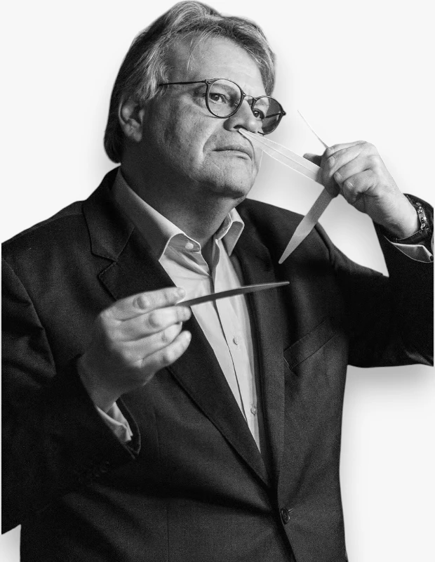 Bir siyah beyaz fotoğrafta, gözlüklü ve kır saçlı Jacques Cavallier, takım elbisesiyle dikkatlice parfüm kokularını değerlendirirken görülüyor; burnuna tuttuğu ince test şeritleriyle koku yaratma sanatının inceliklerini inceliyor ve derinlemesine bir konsantrasyon sergiliyor.