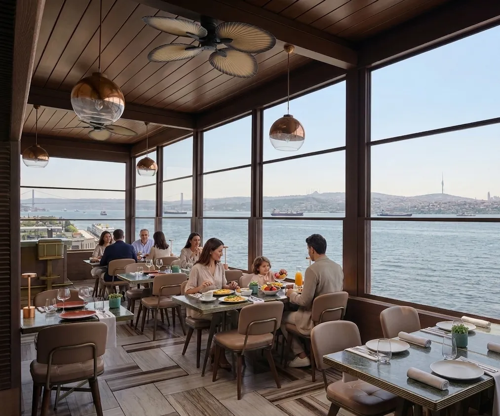 JW Marriott'un İstanbul Boğazı manzaralı şık restoranında, ahşap tavanlı ve modern avizeli bir ortamda, Boğaz Köprüsü ve Çamlıca Kulesi'nin de görüldüğü panoramik manzaraya karşı aileler ve arkadaş grupları kahvaltı keyfi yapıyor.