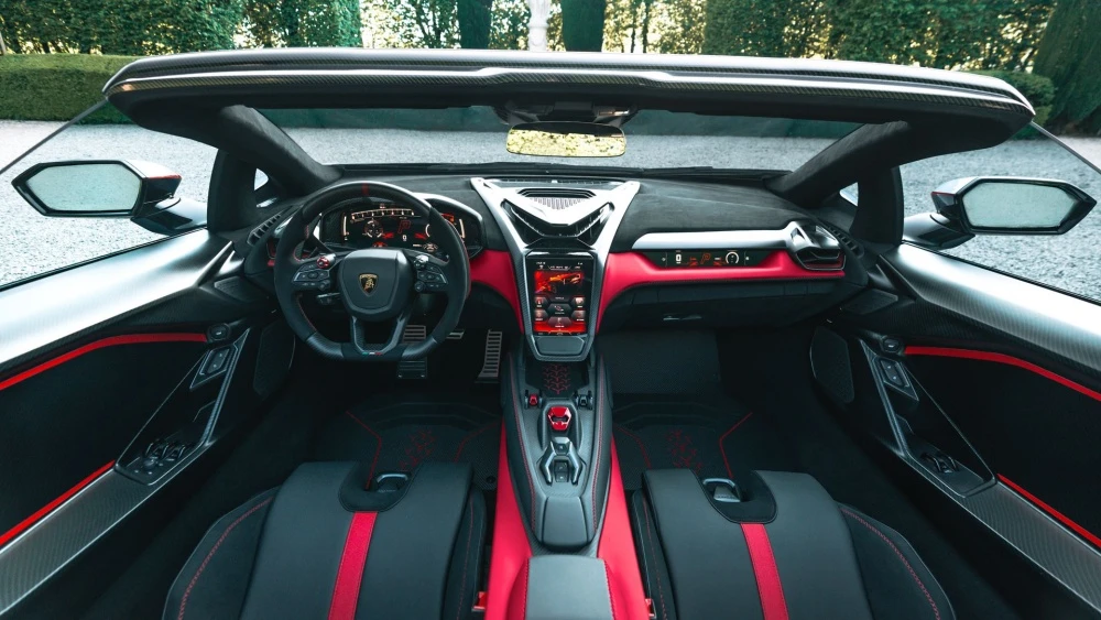 Lamborghini Fenomeno Roadster'ın tepeden çekilmiş bu çarpıcı iç mekan tasarımı görüntüsü, siyah ana tonların kırmızı detaylarla buluştuğu dijital gösterge paneli, merkezi dokunmatik ekran, karbon fiber vurgular ve sportif çizgili koltuklarla yüksek performanslı bir atmosfer sunuyor.
