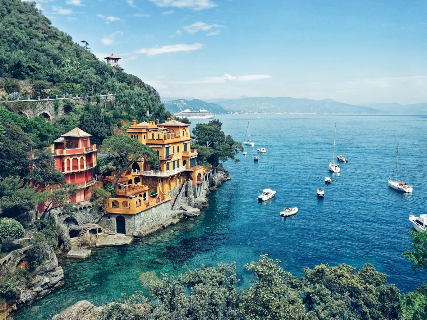 Portofino'nun masmavi sularında yüzen tekneler, yemyeşil yamaçlara kurulu rengarenk Akdeniz evleri ve uzakta görünen dağlarla çevrili büyüleyici manzarası, bu eşsiz destinasyona nasıl gidilir sorusunu akıllara getiriyor.