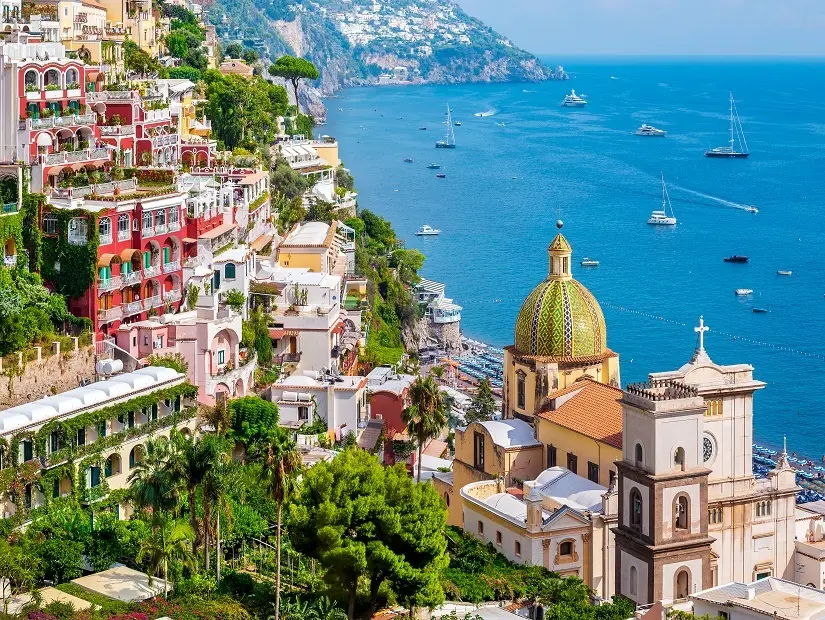 Yemyeşil bitki örtüsüyle kaplı dik bir yamaçta sıralanmış, kırmızı ve pastel tonlardaki çok katlı binaların çevrelediği, parlak mavi denize nazır Positano kasabasının genel görünümünde, ortada yer alan ve canlı yeşil-sarı çinili kubbesiyle öne çıkan Santa Marina Kilisesi'nin silüeti ve denizde yüzen çok sayıda yat ve yelkenli teknenin huzurlu görüntüsü sergileniyor.