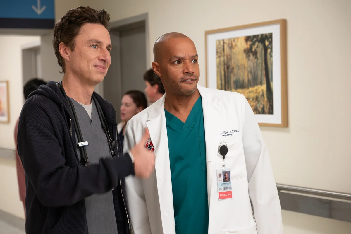Scrubs dizisinin sevilen doktorları Zach Braff ve Donald Faison, bir hastane koridorunda, Braff'ın canlandırdığı JD'nin kapüşonlu üstü ve gri önlüğüyle gülümseyerek eliyle işaret ettiği, Faison'ın canlandırdığı Turk'ün ise beyaz laboratuvar önlüğü içinde şaşkın bir ifadeyle baktığı bir sahne sergiliyor.
