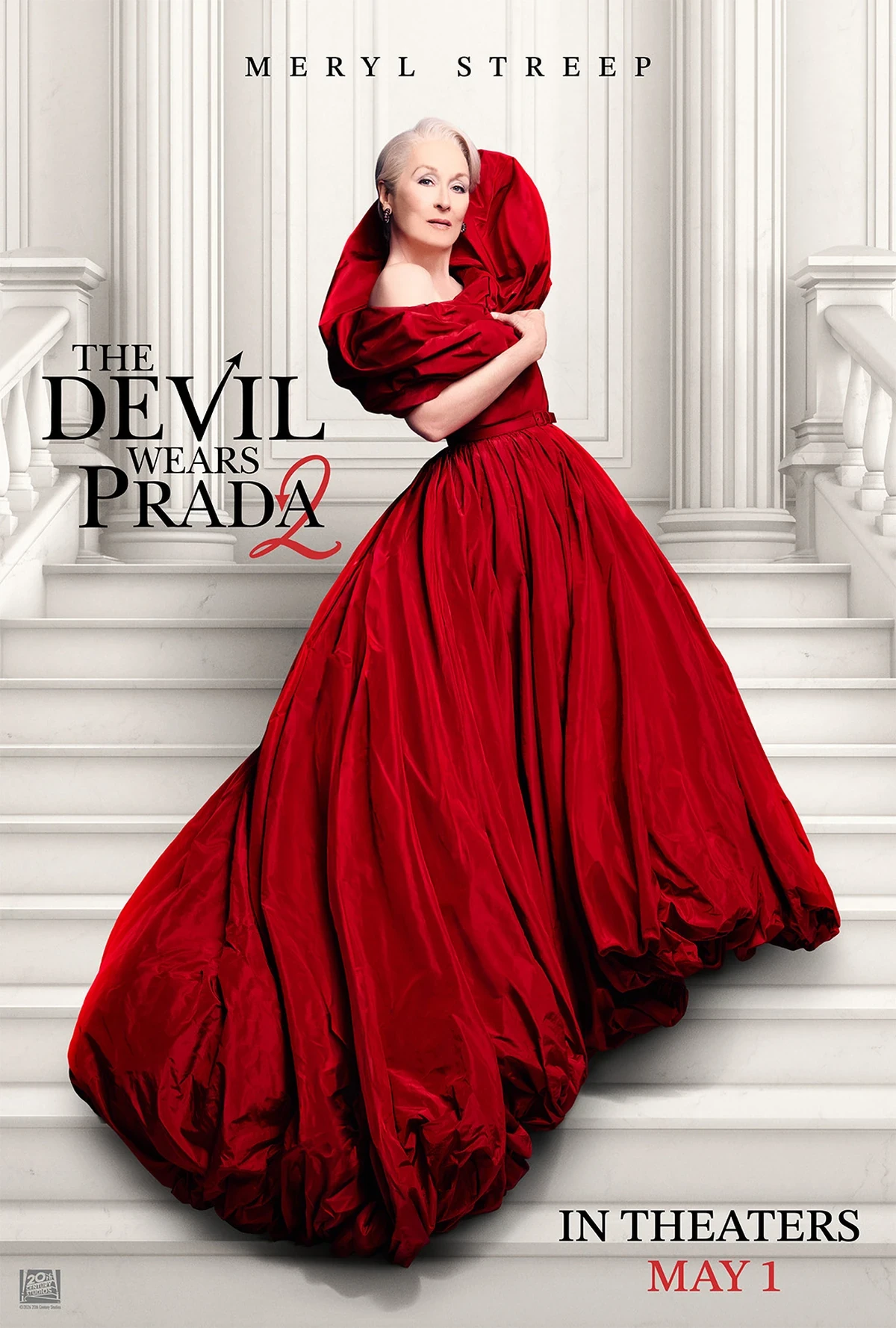 The Devil Wears Prada 2 filminin afişinde, Meryl Streep beyaz mermer merdivenlerin üzerinde dururken, omuzları açık, uçuş uçuş, kabarık ve oldukça dikkat çekici parlak kırmızı bir gece elbisesiyle doğrudan izleyiciye bakıyor.