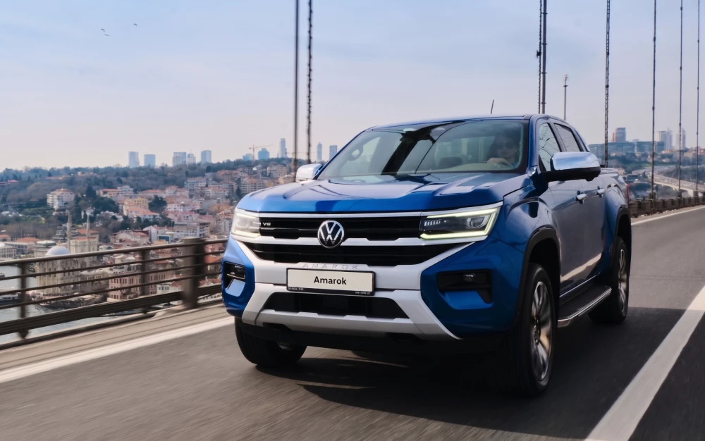 İstanbul Boğazı üzerindeki köprüde dinamik bir şekilde ilerleyen, ön ızgarasında V6 yazısı dikkat çeken parlak mavi renkteki yeni nesil Volkswagen Amarok pickup, şehrin panoramik manzarası eşliğinde güçlü duruşunu sergiliyor.