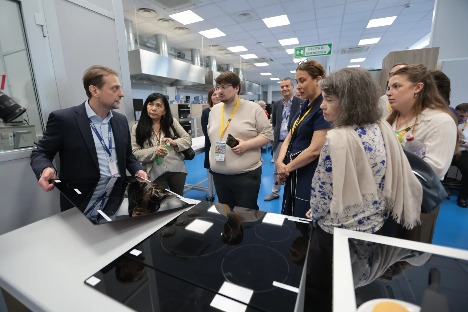 Beko Europe'un Kuzey İtalya'daki tasarım kalbi Cassinetta'da, bir teknoloji uzmanı, ziyaretçilere modern mutfakların geleceğini şekillendiren ankastre pişirici ürünlerin yeni teknoloji ve tasarım detaylarını yansıtan parlak siyah cam yüzeyleri tanıtırken, grubun ürün geliştirme ve inovasyon süreçlerine ışık tutuyor.