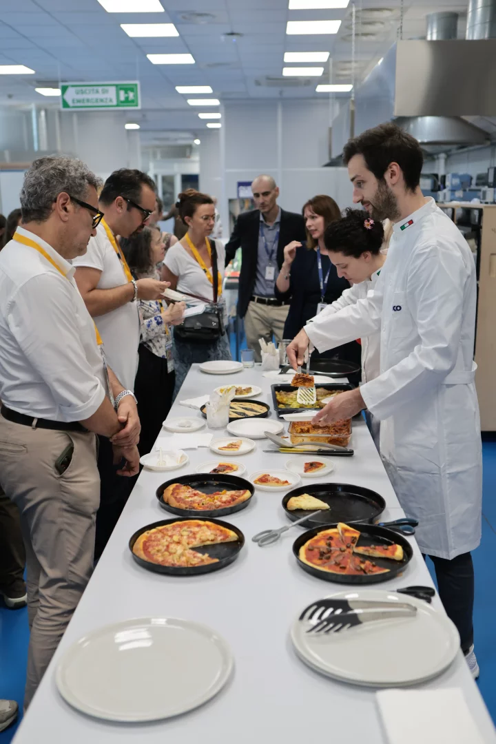 Cassinetta'daki Food Tech Lab'i ziyareti sırasında, gıda bilimcileri ve mühendislerin, ileri mutfak teknolojileriyle hazırladığı ve profesyonel mutfak performansını evlere taşıyan yemekleri beyaz önlüklü bir uzman misafirlere servis ediyor.