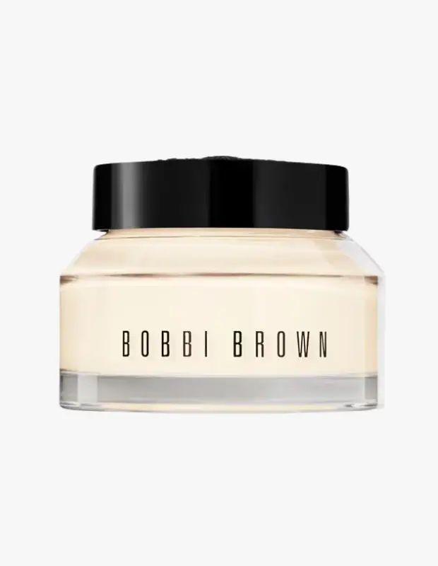BOBBI BROWN markasının adının şık bir şekilde görüldüğü şeffaf cam kavanozda, siyah kapaklı ve hafif sarımsı tonda kremsi yapısıyla dikkat çeken bu makyaj bazı, beyaz bir arka planda özenle sergileniyor.