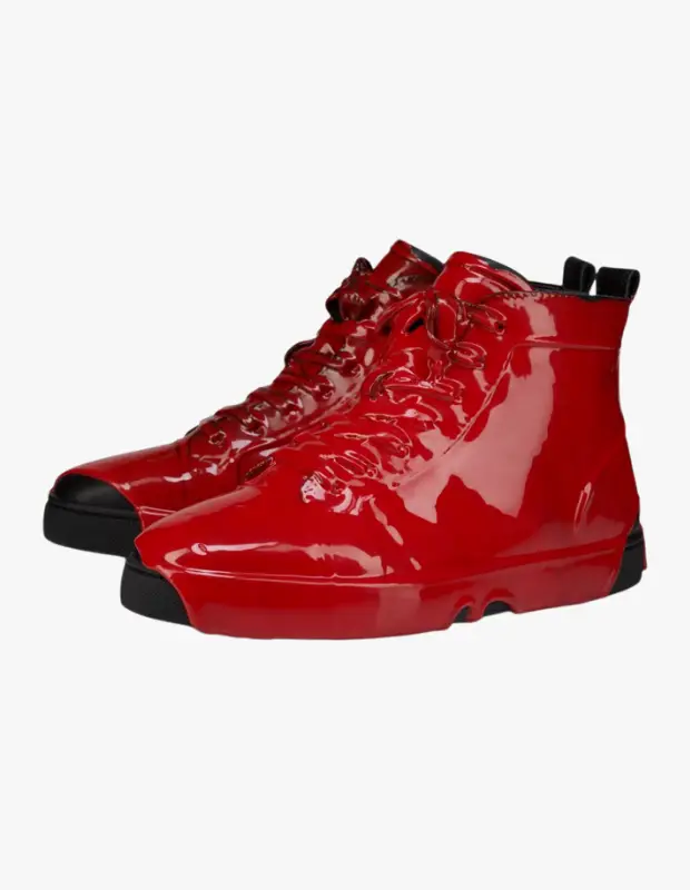 Beyaz bir arka plan önünde, Christian Louboutin markasının Molten Louis serisinden, Sonbahar-Kış koleksiyonuna ait, erimiş metal veya ıslak parlaklığa sahip göz alıcı kırmızı renkte iki yüksek bilekli erkek spor ayakkabısı sergileniyor.