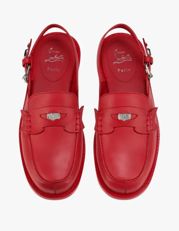 Beyaz bir zeminde sergilenen, parlak kırmızı renkteki Christian Louboutin The Asclepius Sling erkek mokasen ayakkabıları, kalın tırtıklı tabanları, arkası askılı tasarımları ve ön kısımlarındaki gümüş renkli metal toka detaylarıyla Sonbahar/Kış koleksiyonundan çarpıcı bir görünüm sunuyor.