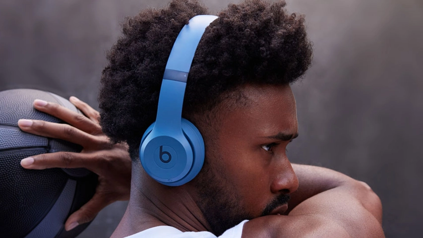 Koyu renkli, dokulu bir topu başının arkasında tutarken mavi Beats kulaklığını takmış, konsantre bir ifadeyle sağa doğru bakan kıvırcık saçlı ve sakallı bir adamın yakın çekimi, spor yaparken veya günlük kullanımda en iyi Beats kulaklık performansı için ilham veriyor.