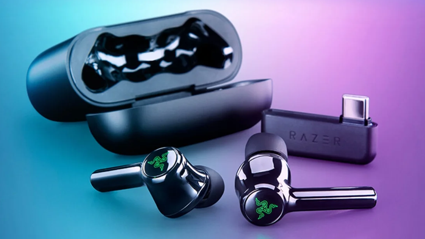 Ön planda, parlak yeşil Razer logosuyla dikkat çeken iki adet koyu renkli Razer Hammerhead Pro HyperSpeed kablosuz kulaklık, arkasında kapağı açık şarj kutusu ve üzerinde Razer yazısı bulunan bir USB-C dongle, mavi, yeşil ve mor renk geçişli bir zeminde sergileniyor.