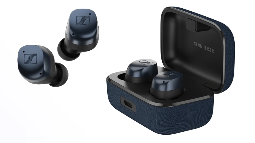 Solda yüzen iki adet koyu mavi Sennheiser Momentum True Wireless 4 kulaklık ile sağda lacivert kumaş dokulu açık şarj kutusunun içinde duran aynı model kulaklıkların beyaz bir zeminde ürün detaylarını net bir şekilde gösteren bir yakın çekim.
