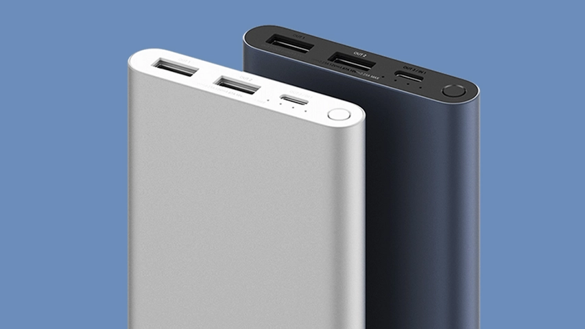 İki adet Xiaomi Powerbank, biri gümüş rengi önde ve diğeri koyu gri arkada olmak üzere açık mavi bir arka plan üzerinde, şarj ve çıkış portları ile güç düğmeleri net bir şekilde görünecek şekilde açılı bir şekilde duruyorlar, bu da Xiaomi'nin 22.5W hızlı şarj kapasiteli ürünlerini sergiliyor.